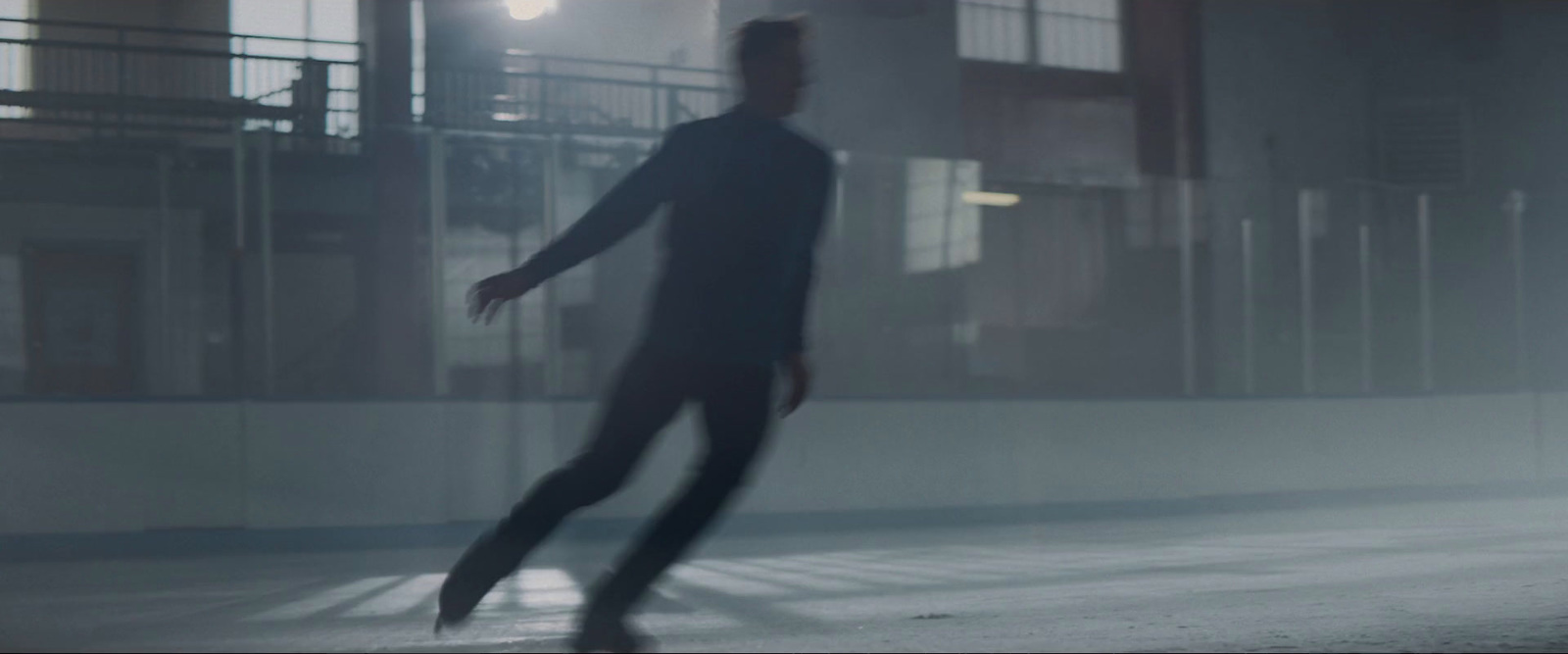 a man in a black suit skating on a rink