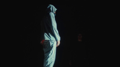 a person in a blue coverall standing in the dark