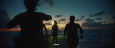 a group of people walking down a pier at night