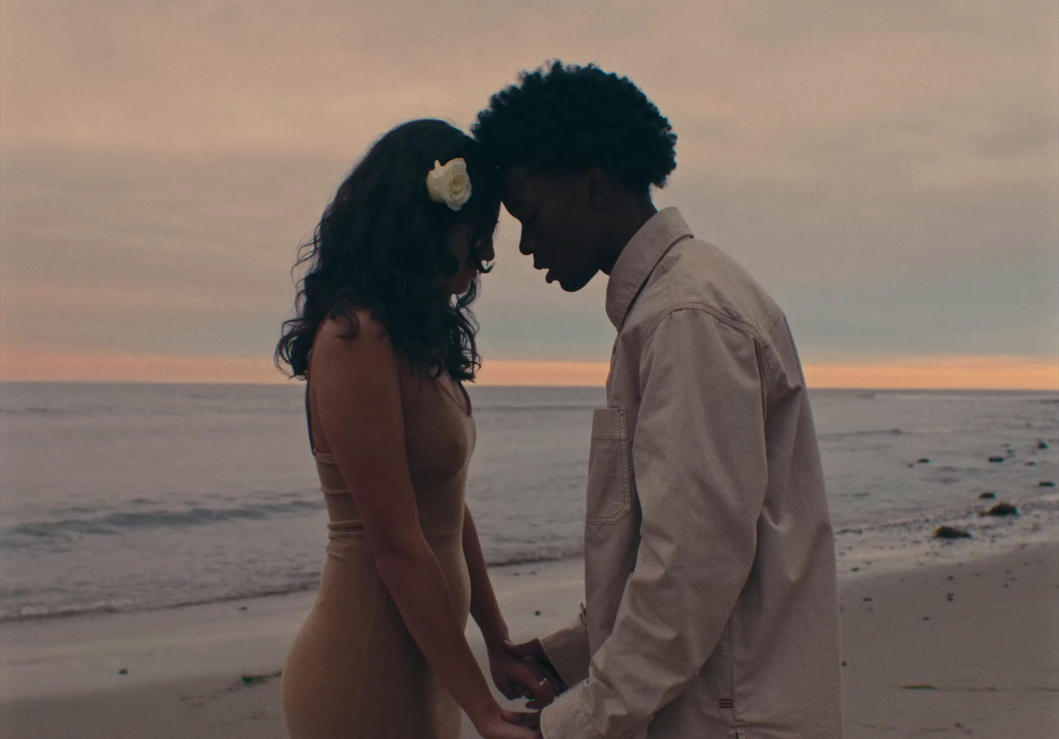 a man and a woman standing on top of a beach