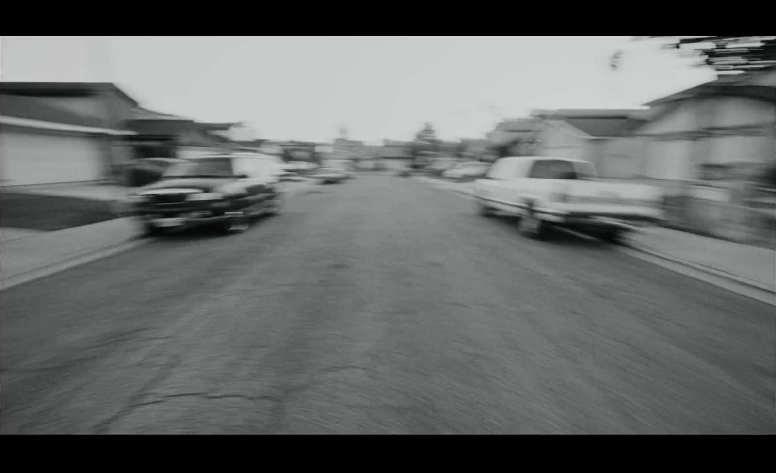 a black and white photo of cars driving down a street