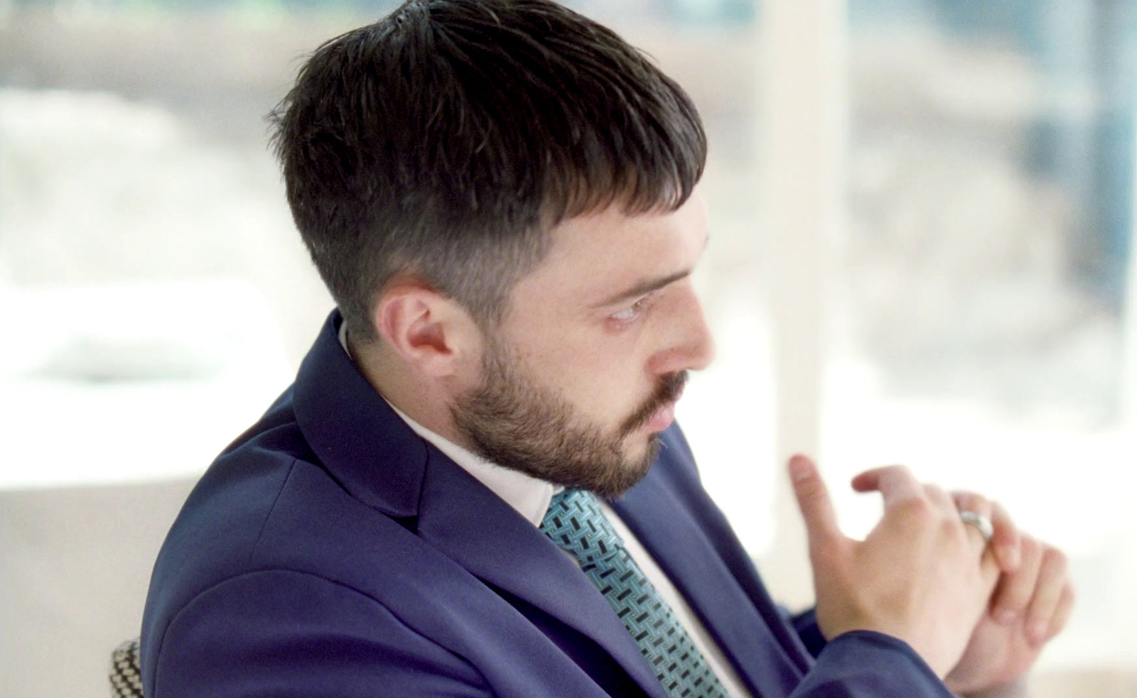 a man in a suit and tie is holding his hands together