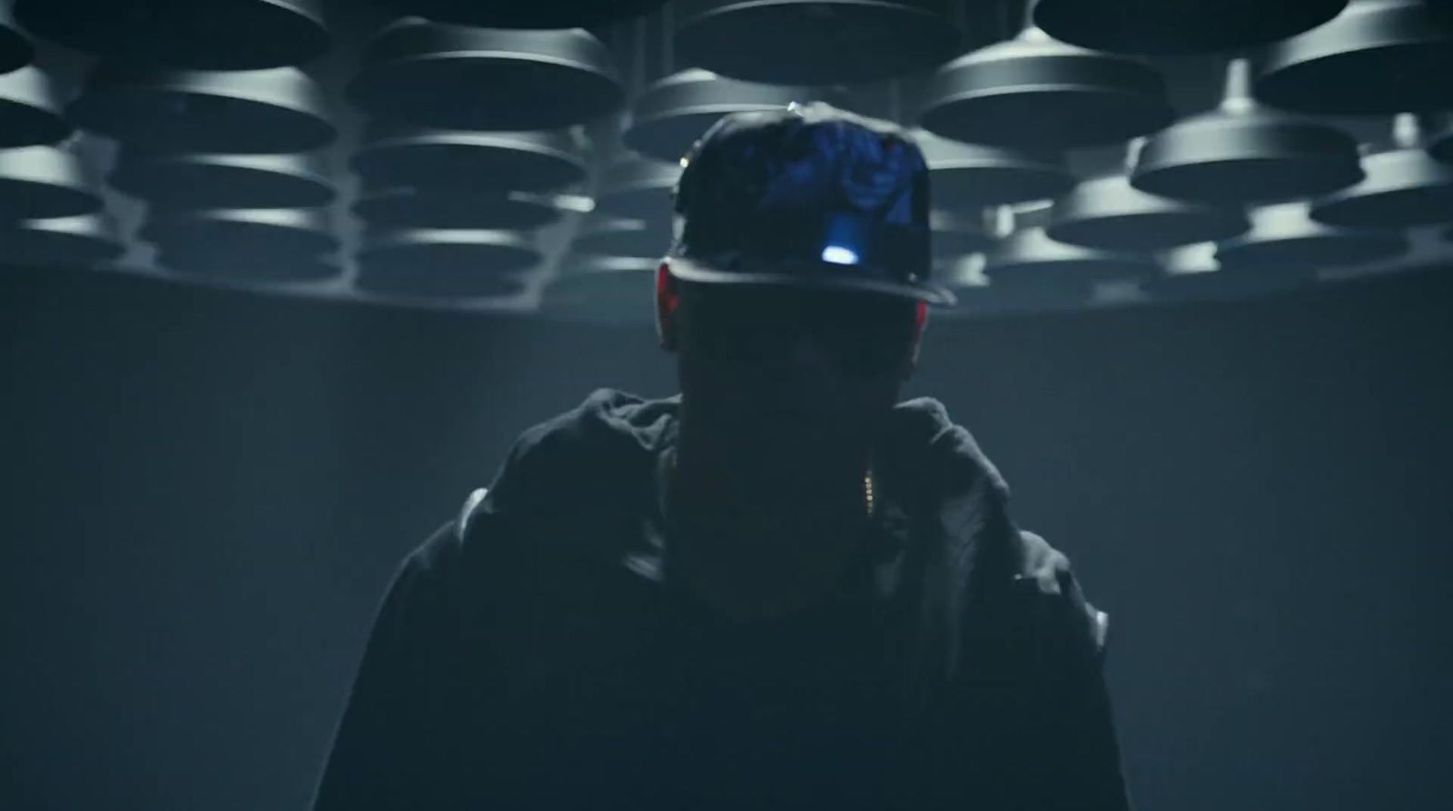 a man with a blue hat standing in a dark room