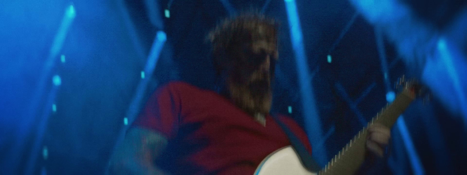 a man playing a guitar in a room with blue lights