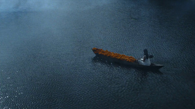 a man in a boat with orange flowers floating on the water