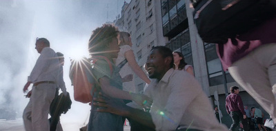 a group of people walking down a street next to tall buildings