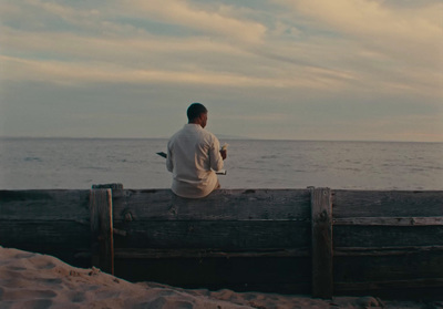 a man sitting on a bench looking out at the ocean