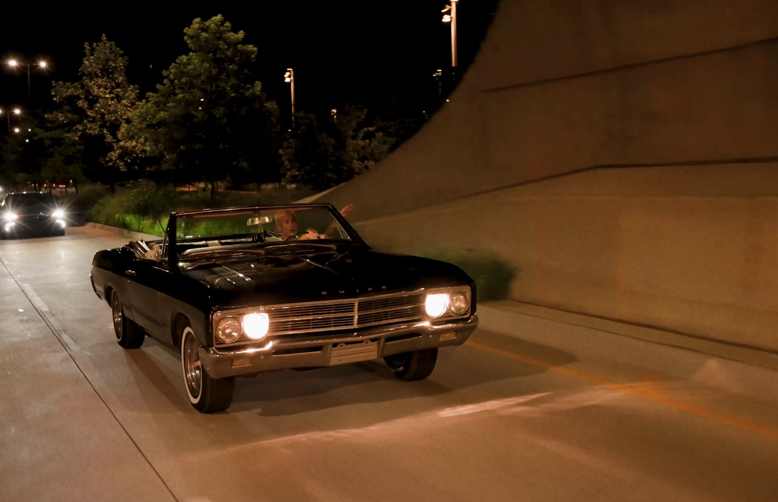 a black truck driving down a street at night