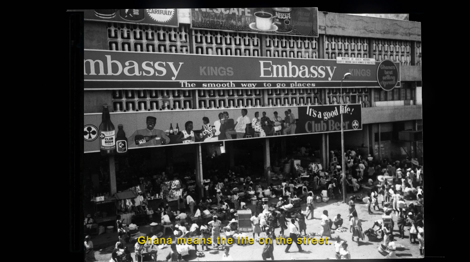 a black and white photo of a crowd of people in front of a building