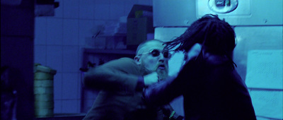 two men fighting in a room with a blue light