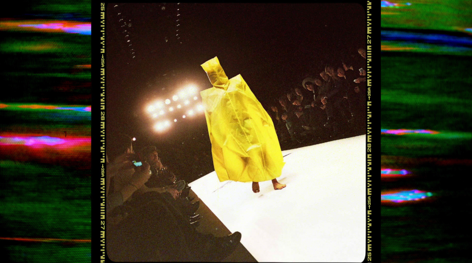 a person in a yellow raincoat walking down a runway