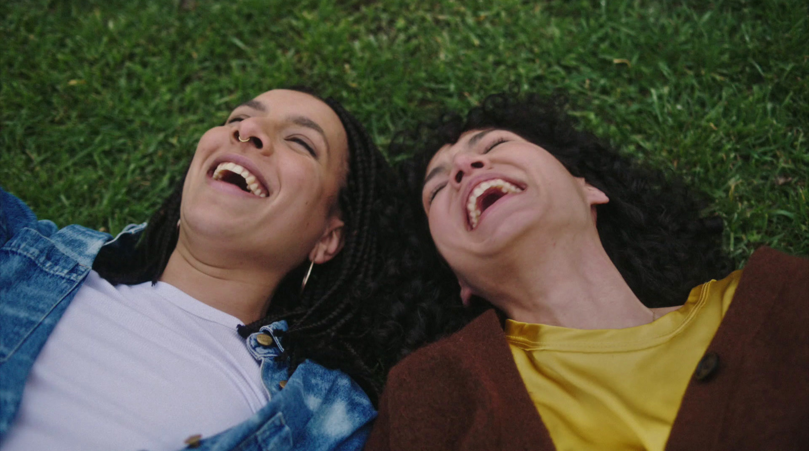 a couple of people laying on top of a lush green field