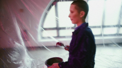 a young boy in a purple shirt painting a wall