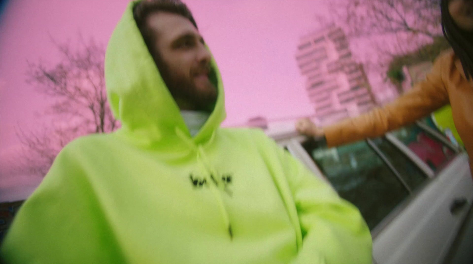 a man in a neon green hoodie standing next to a woman