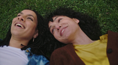 a couple of people laying on top of a lush green field