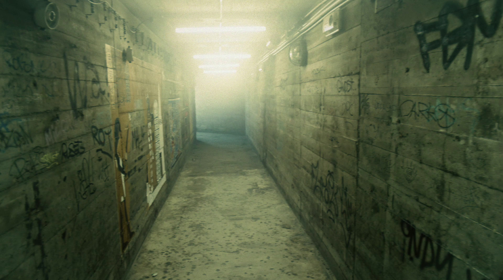 a long narrow hallway with graffiti on the walls