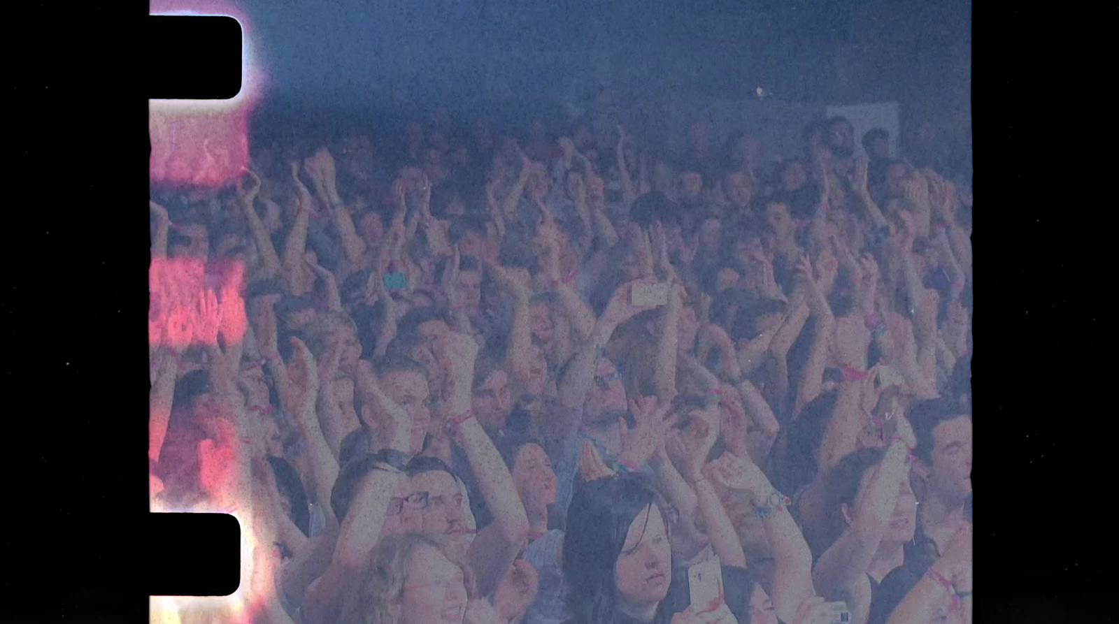 a crowd of people at a concert with their hands in the air