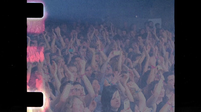 a crowd of people at a concert with their hands in the air