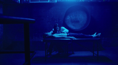 a man and a woman laying on a table in a dark room